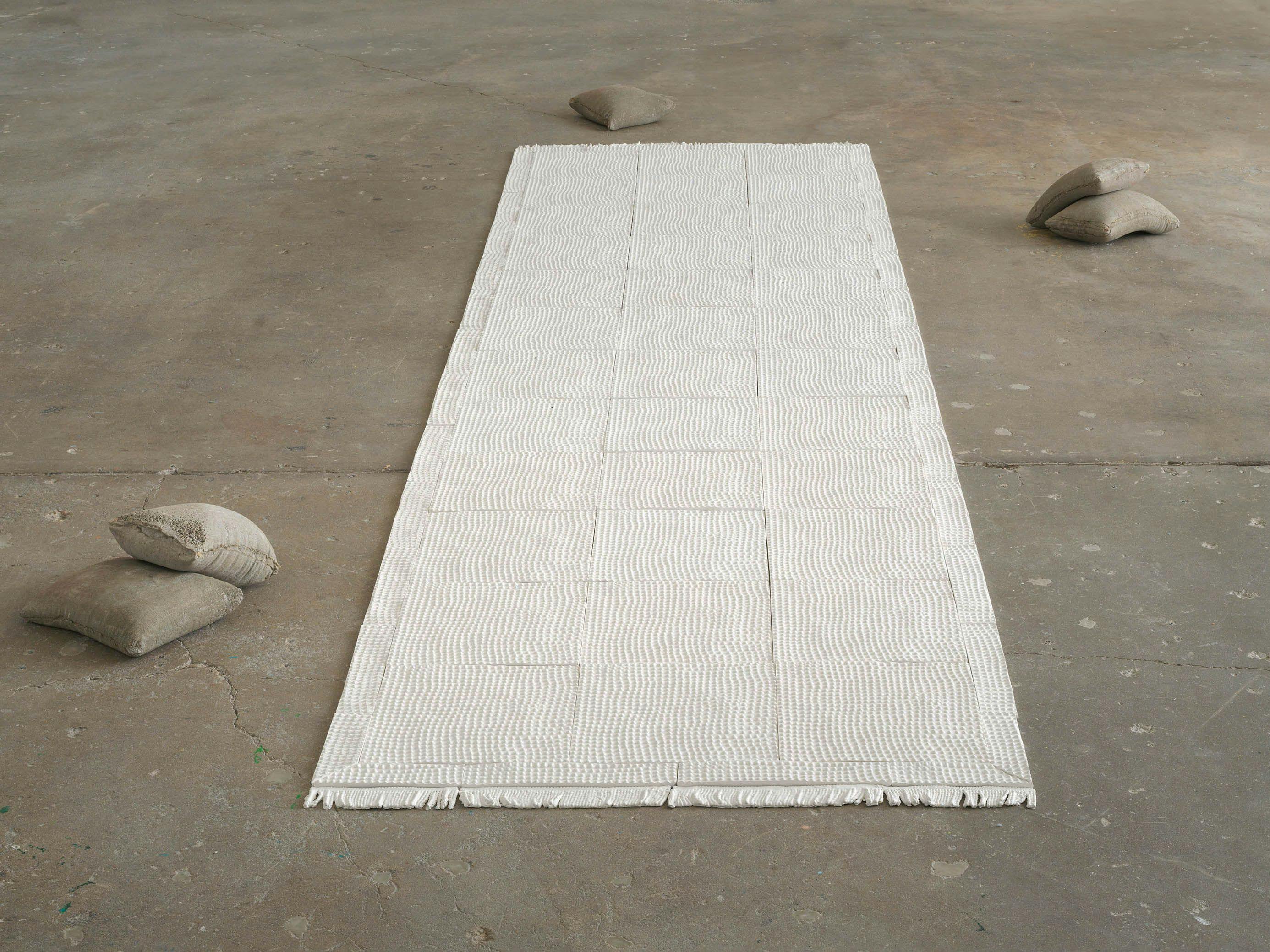 An installation artwork by Haley Darya Parsa, titled Bakhtiari Rug & 300 lbs. of Basmati Rice, dated in 2018 and 2024.