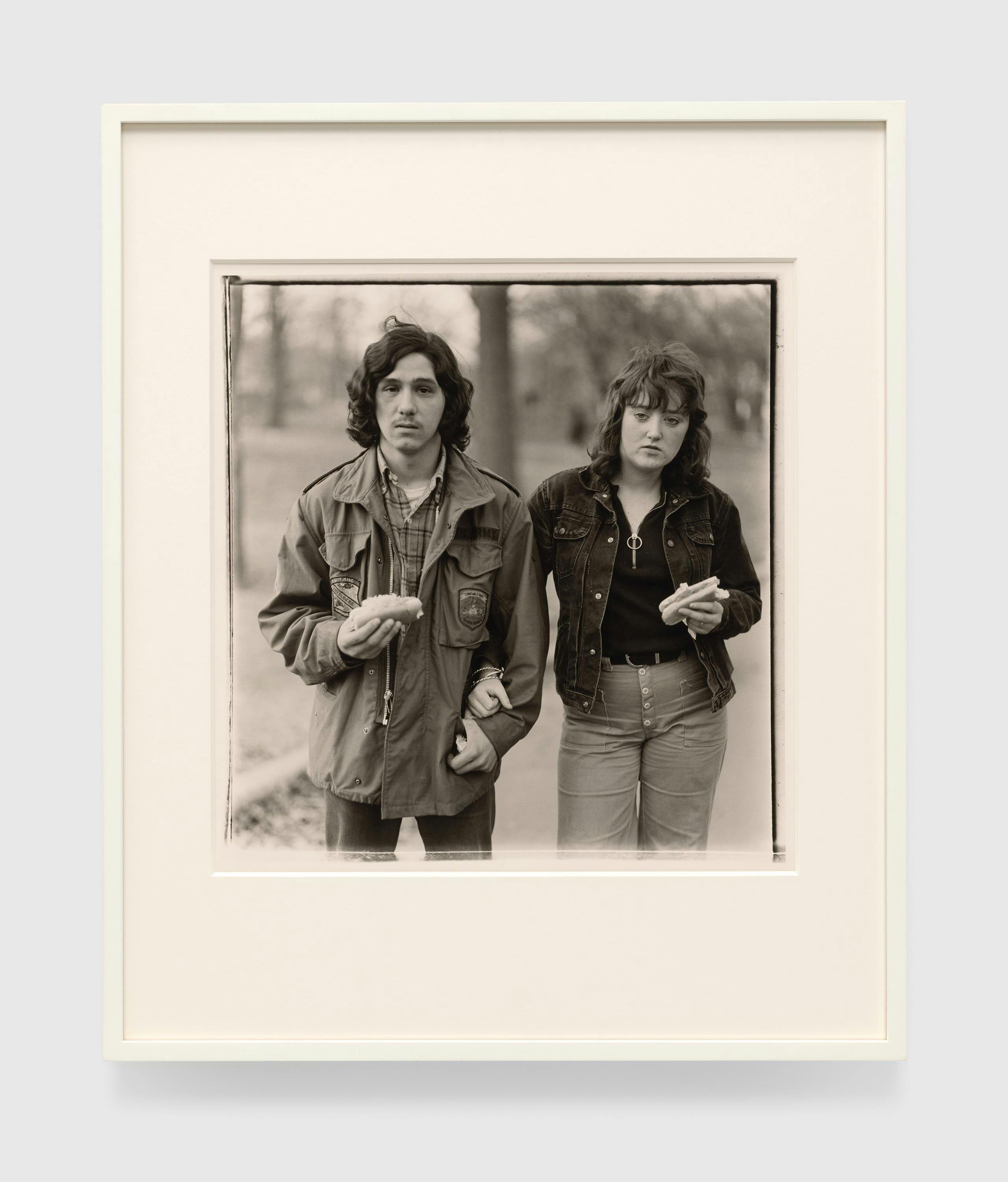 A Gelatin silver print by Diane Arbus, titled A young man and his girlfriend with hot dogs in the park, N.Y.C. 1971, dated 1971.