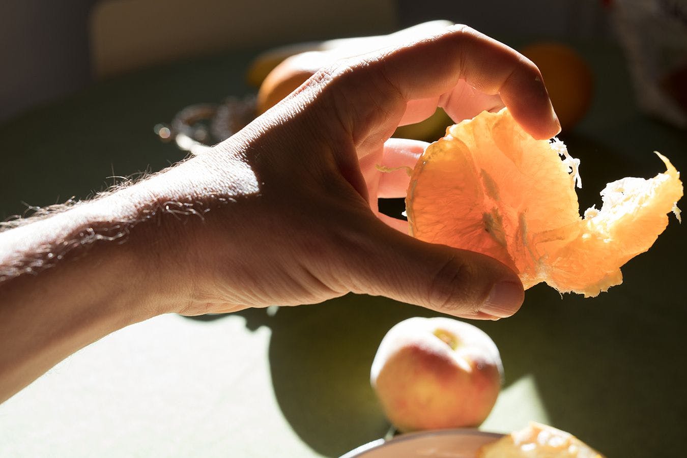 An image of a man's hand grabbing a peeled orange with backlit sunlight, titled Sicily Morning by Wolfgang Tillmans, dated 2018